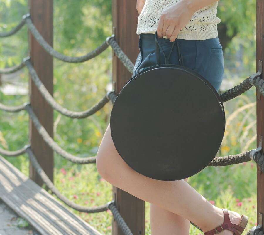 fekete kör alakú bőr variálható táska női modell kezében tartva
