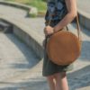 lulla nevű kör alakú natúr színű marhabőr variálható desing táska női modell vállán